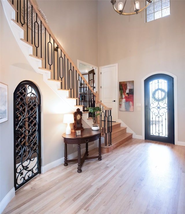 entrance foyer featuring baseboards, a chandelier, stairs, a high ceiling, and wood finished floors