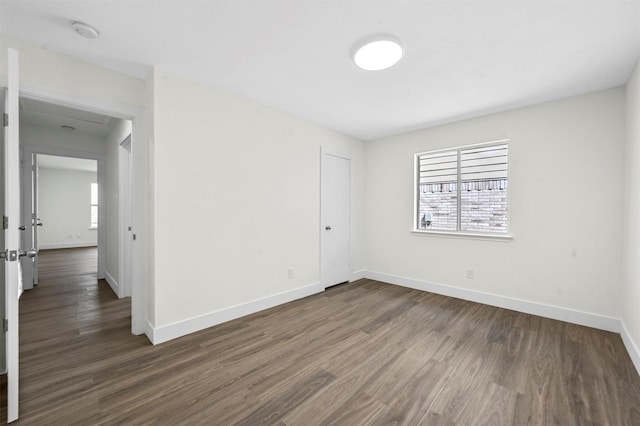 unfurnished room featuring baseboards and dark wood-style flooring