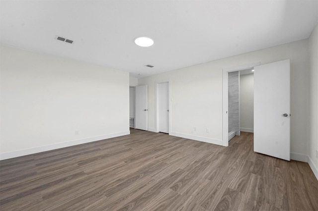 unfurnished room featuring wood finished floors, visible vents, and baseboards