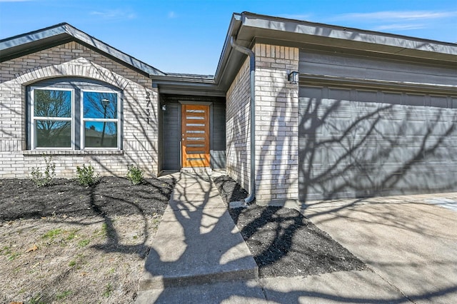 view of front of home with concrete driveway, an attached garage, and brick siding