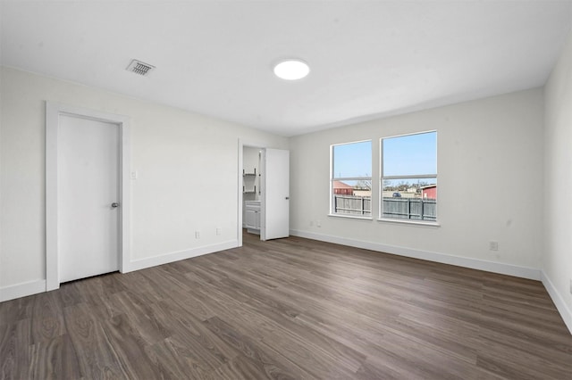 unfurnished bedroom with dark wood-style floors, visible vents, and baseboards