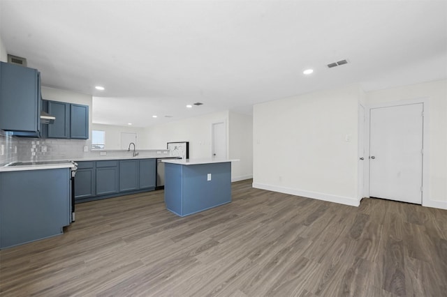 kitchen featuring visible vents, light countertops, decorative backsplash, wood finished floors, and blue cabinets