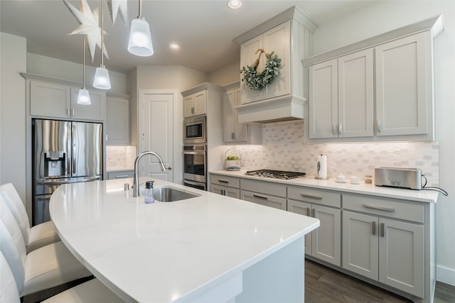 kitchen featuring backsplash, pendant lighting, dark wood-style floors, stainless steel appliances, and a sink