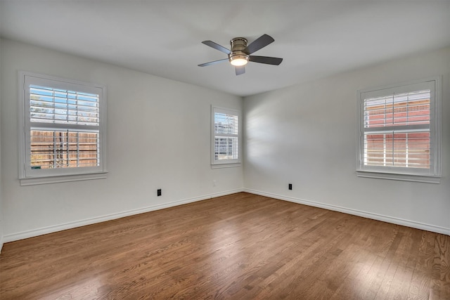 spare room with baseboards, wood finished floors, and a ceiling fan