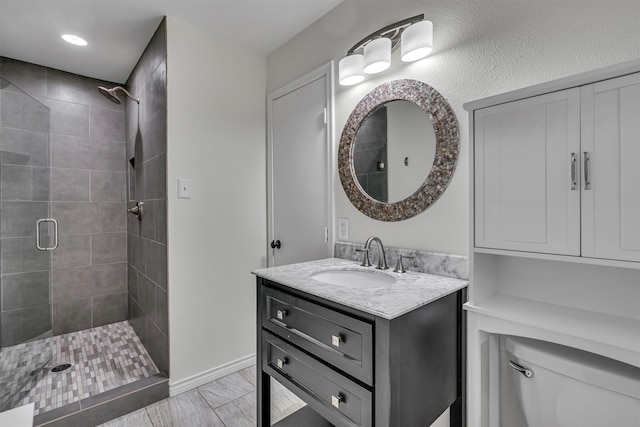 bathroom featuring vanity, toilet, baseboards, and a stall shower