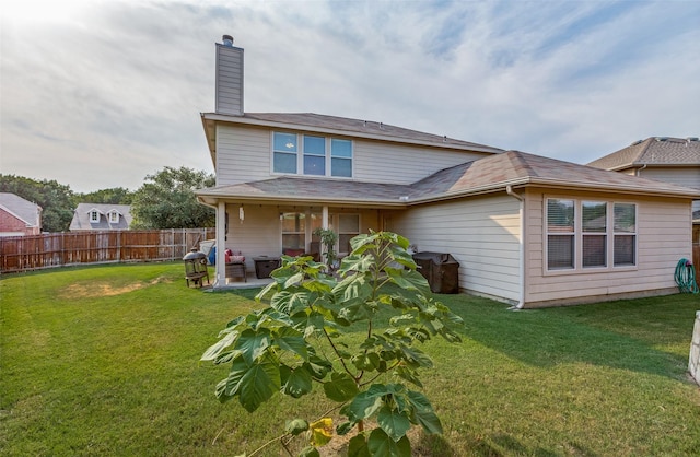 rear view of property featuring fence, a chimney, a lawn, and a patio