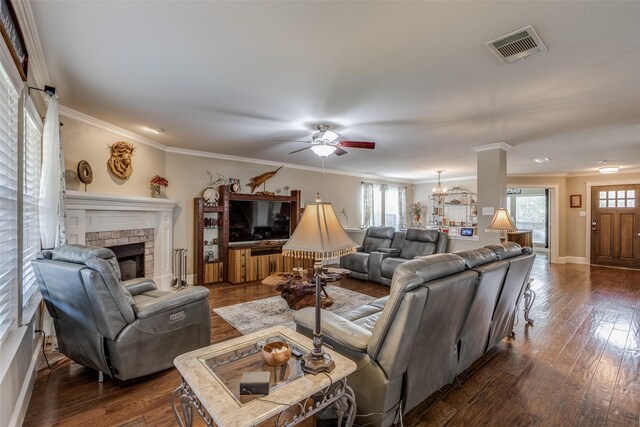 living area featuring visible vents, ornamental molding, ceiling fan, and a stone fireplace