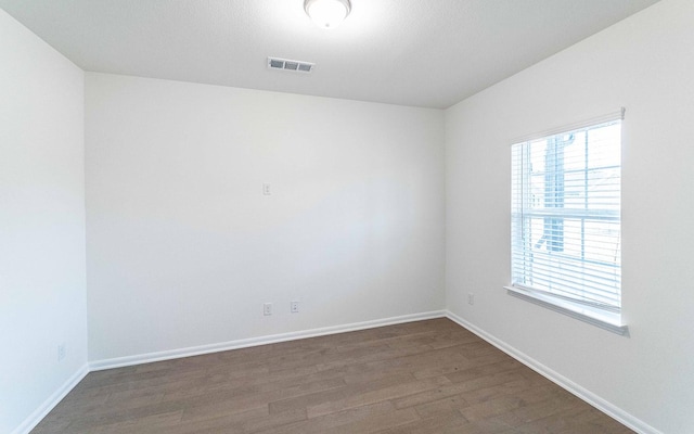 unfurnished room with visible vents, baseboards, and wood finished floors