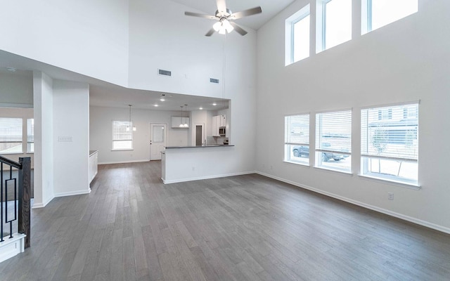 unfurnished living room with visible vents, baseboards, dark wood-type flooring, and a ceiling fan