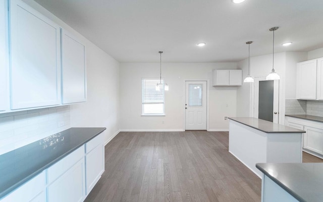 kitchen with white cabinetry, wood finished floors, baseboards, and backsplash