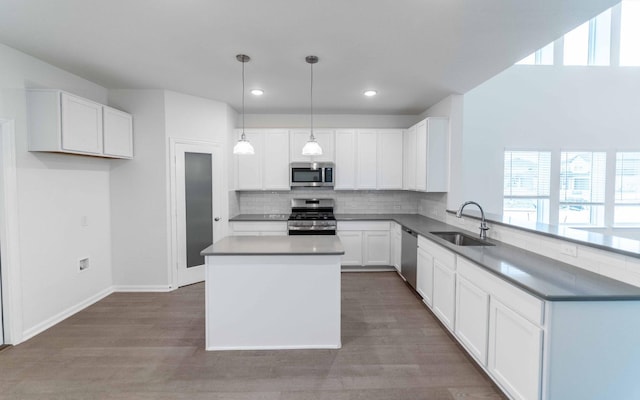 kitchen featuring a sink, backsplash, wood finished floors, a center island, and stainless steel appliances