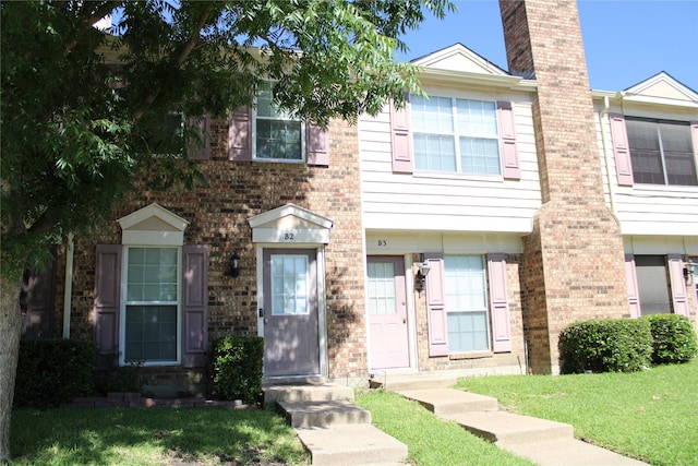 multi unit property with a front yard, brick siding, and a chimney