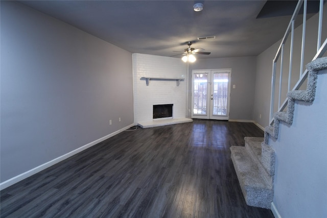 unfurnished living room with dark wood-style floors, french doors, a fireplace, baseboards, and stairs