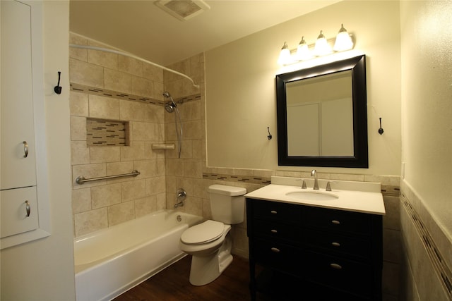 full bath featuring visible vents, tub / shower combination, toilet, vanity, and tile walls