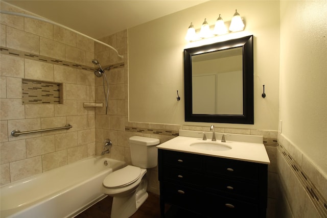 bathroom with vanity, bathtub / shower combination, wainscoting, tile walls, and toilet