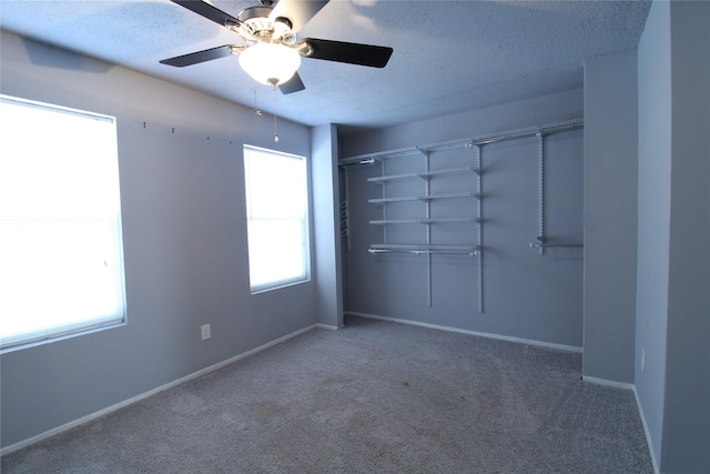 carpeted empty room featuring a textured ceiling, baseboards, and a ceiling fan