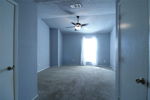 carpeted empty room featuring baseboards, visible vents, a textured ceiling, and ceiling fan