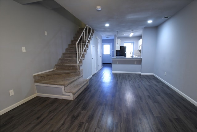 interior space with stairway, baseboards, recessed lighting, dark wood-style flooring, and a sink