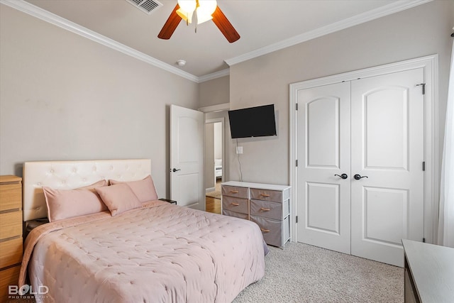 bedroom with visible vents, light carpet, ornamental molding, a closet, and ceiling fan