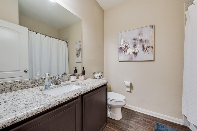 full bathroom with toilet, vanity, baseboards, and wood finished floors