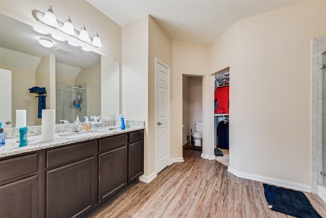 bathroom with visible vents, toilet, a stall shower, wood finished floors, and vanity