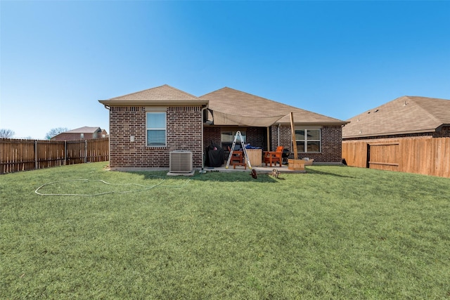 rear view of house featuring brick siding, a fenced backyard, and central AC