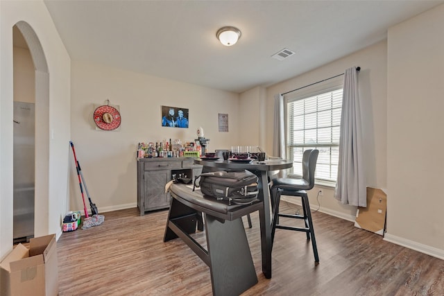 dining area featuring visible vents, arched walkways, baseboards, and wood finished floors