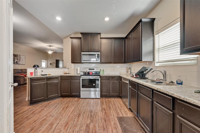 kitchen featuring light wood-style flooring, a sink, tasteful backsplash, stainless steel appliances, and dark brown cabinets