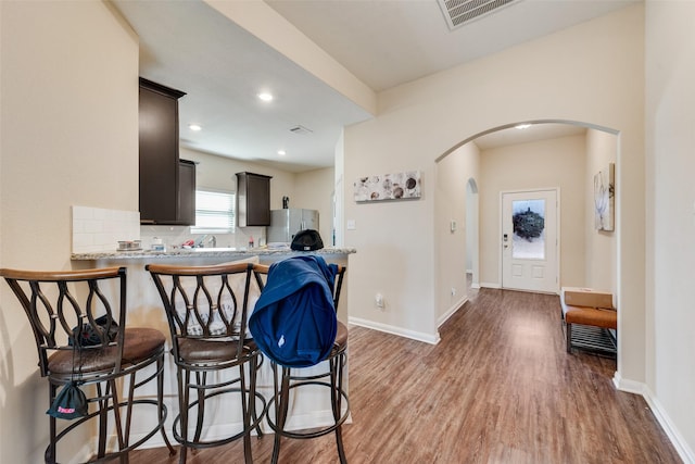 kitchen featuring visible vents, arched walkways, a kitchen bar, and freestanding refrigerator