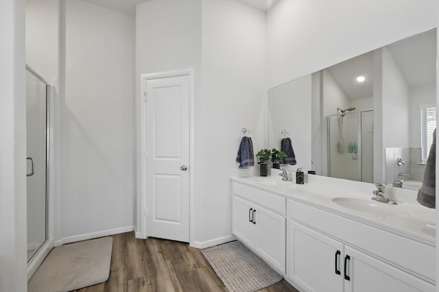 full bath featuring a sink, wood finished floors, a stall shower, and double vanity