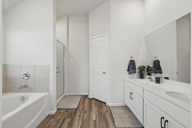 full bathroom featuring a bath, a sink, double vanity, and wood finished floors