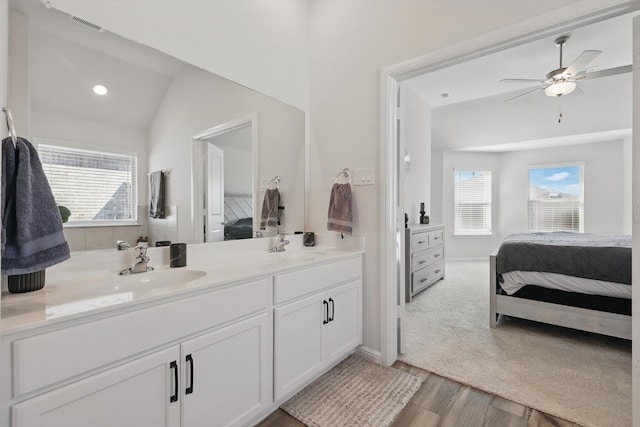 ensuite bathroom featuring double vanity, connected bathroom, ceiling fan, and a sink