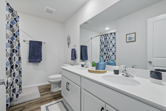 bathroom with visible vents, toilet, wood finished floors, and a sink