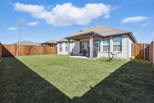 back of property featuring a patio, a yard, a fenced backyard, and brick siding