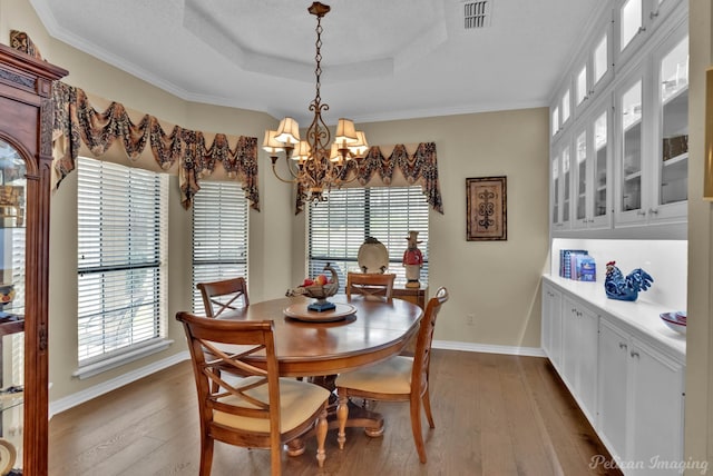 dining space featuring baseboards, visible vents, a tray ceiling, dark wood-style flooring, and a notable chandelier