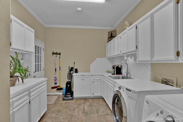 clothes washing area featuring cabinet space, ornamental molding, a sink, a textured ceiling, and washer and dryer