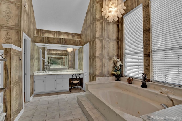 full bathroom featuring tile patterned flooring, a jetted tub, vanity, and an inviting chandelier