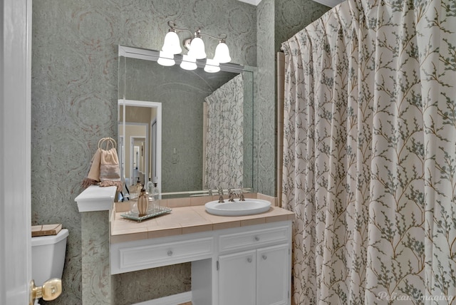 bathroom with wallpapered walls, curtained shower, toilet, and vanity