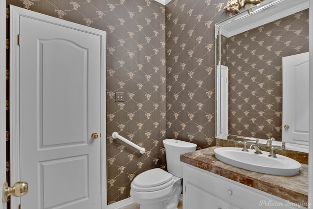 half bathroom featuring toilet, vanity, and wallpapered walls