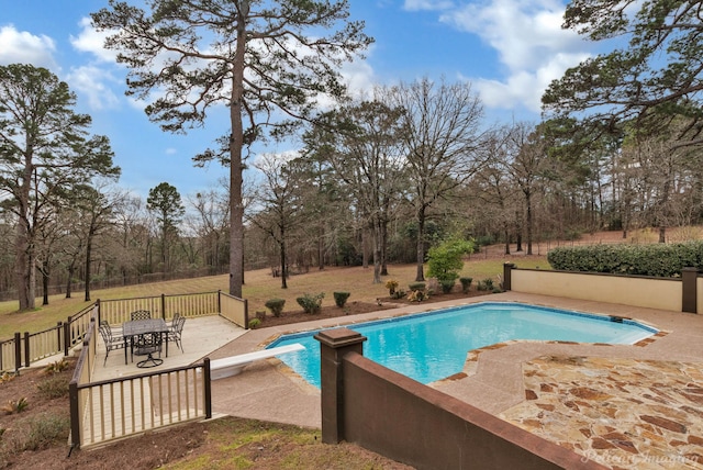 view of swimming pool featuring a diving board, fence, a patio area, and a fenced in pool