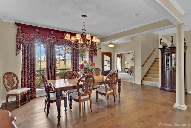 dining space with stairway, wood finished floors, and ornate columns