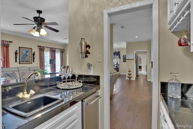 kitchen with a sink, dark countertops, wood finished floors, open floor plan, and white cabinets