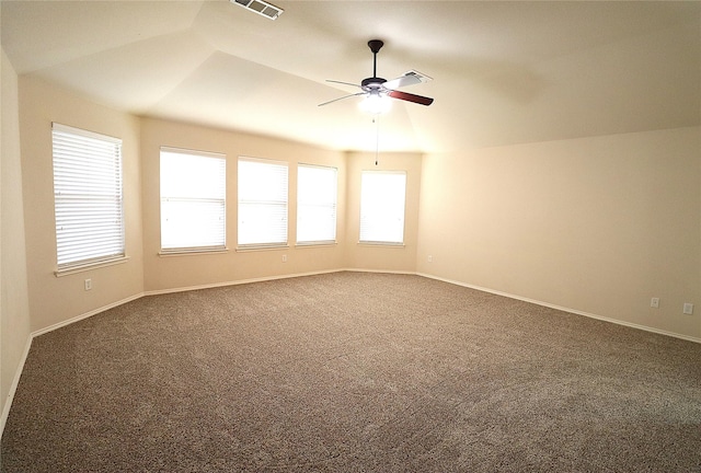 empty room featuring visible vents, dark carpet, a ceiling fan, and baseboards