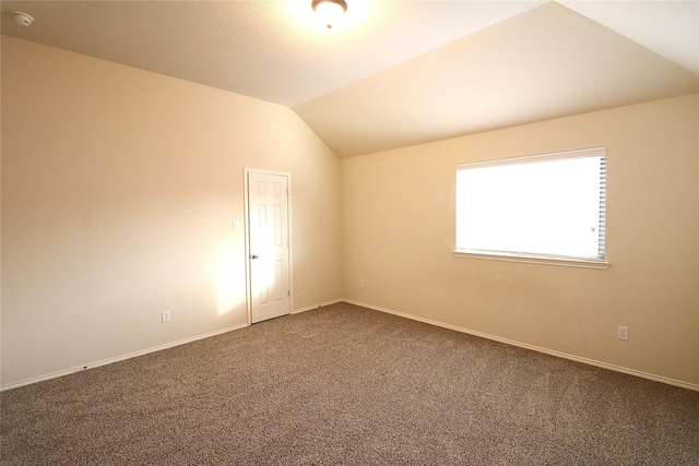 carpeted spare room with baseboards and lofted ceiling