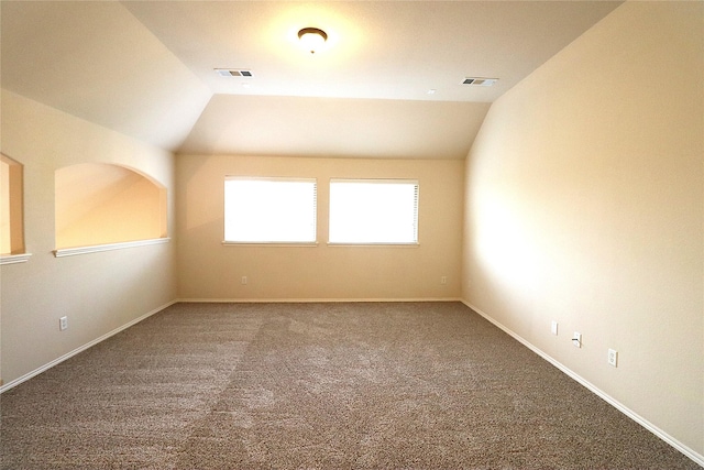 carpeted spare room with visible vents, baseboards, and vaulted ceiling