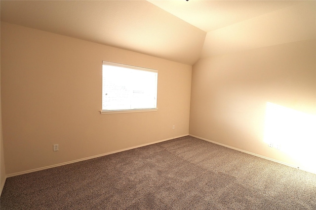 carpeted spare room with lofted ceiling and baseboards