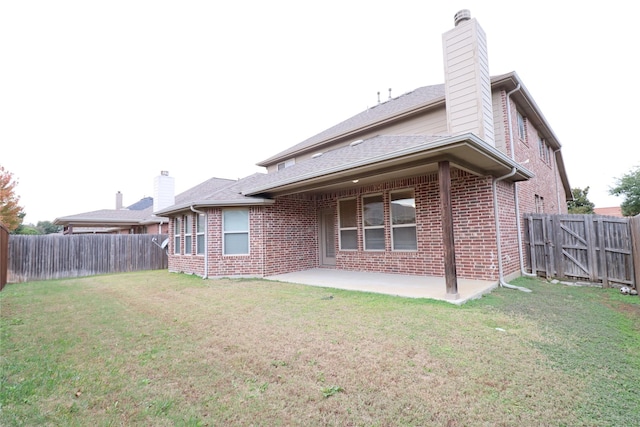 back of property with a patio area, brick siding, a fenced backyard, and a lawn