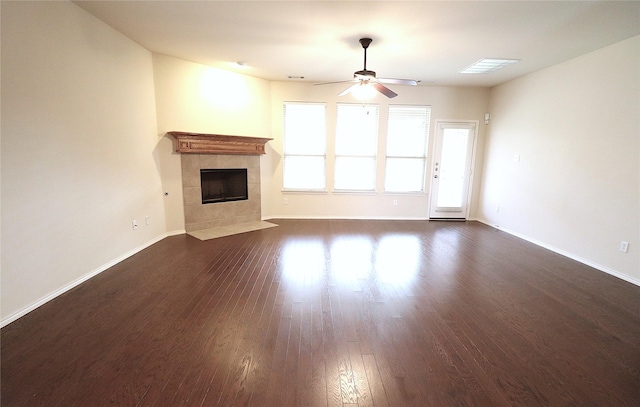 unfurnished living room featuring a fireplace, baseboards, dark wood-type flooring, and ceiling fan