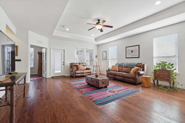 living room featuring visible vents, a raised ceiling, baseboards, and hardwood / wood-style floors