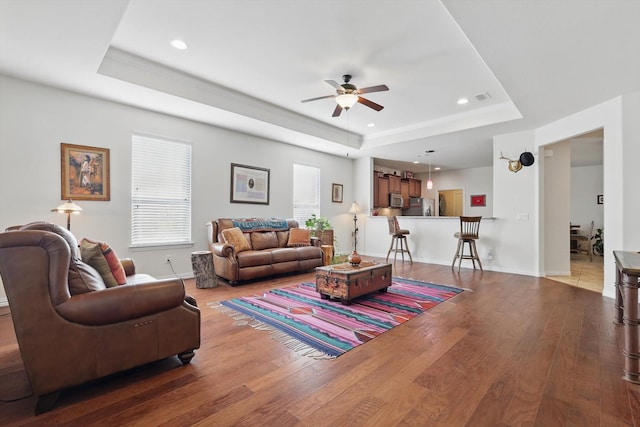 living room featuring recessed lighting, a tray ceiling, and wood finished floors